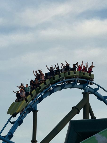 Riders with arms raised on a train cresting Lightning Run's blue track
